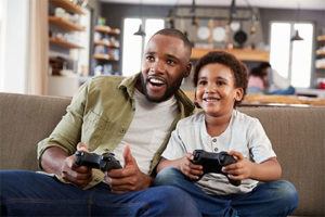 Père et fils jouant à la console (PS4)